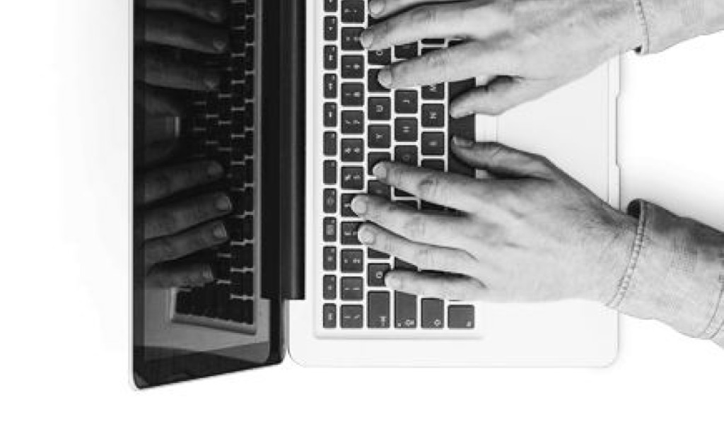 Hands typing on a laptop
